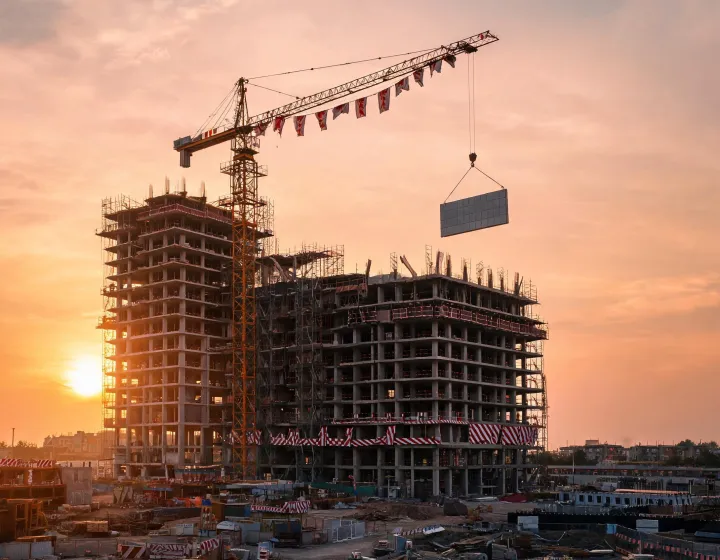 Tower crane lifting precast panels on high-rise construction site