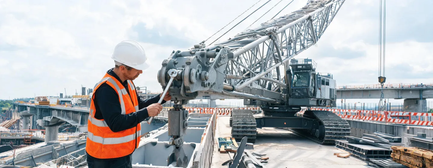 Field engineer inspecting crawler crane boom pin on jobsite